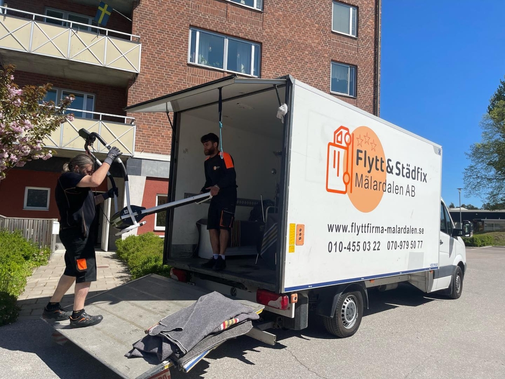 Två flyttgubbar som packar på flyttbil
