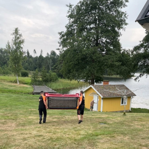 Två medarbetare från Flytt och städfix Mälardalen AB flyttar en soffa tillsammans med noggrannhet.