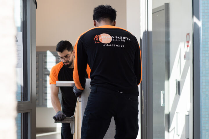 A member of the Flytt och Städfix Mälardalen AB team loading a bed into a van during a move.