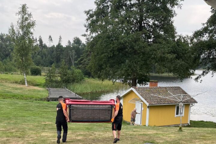 Two members of the Flytt och Städfix Mälardalen AB team carefully moving a sofa together.