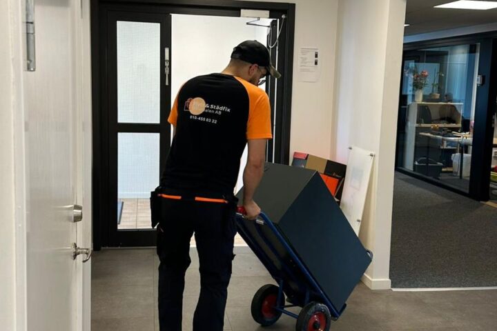 Medarbetare från Flytt och städfix Mälardalen AB flyttar ett kassaskåp med hjälp av en kärra.