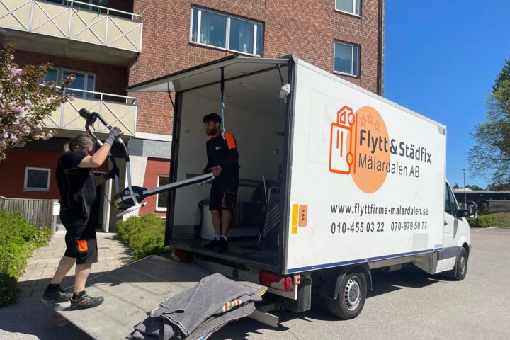 Två flyttgubbar som packar på flyttbil
